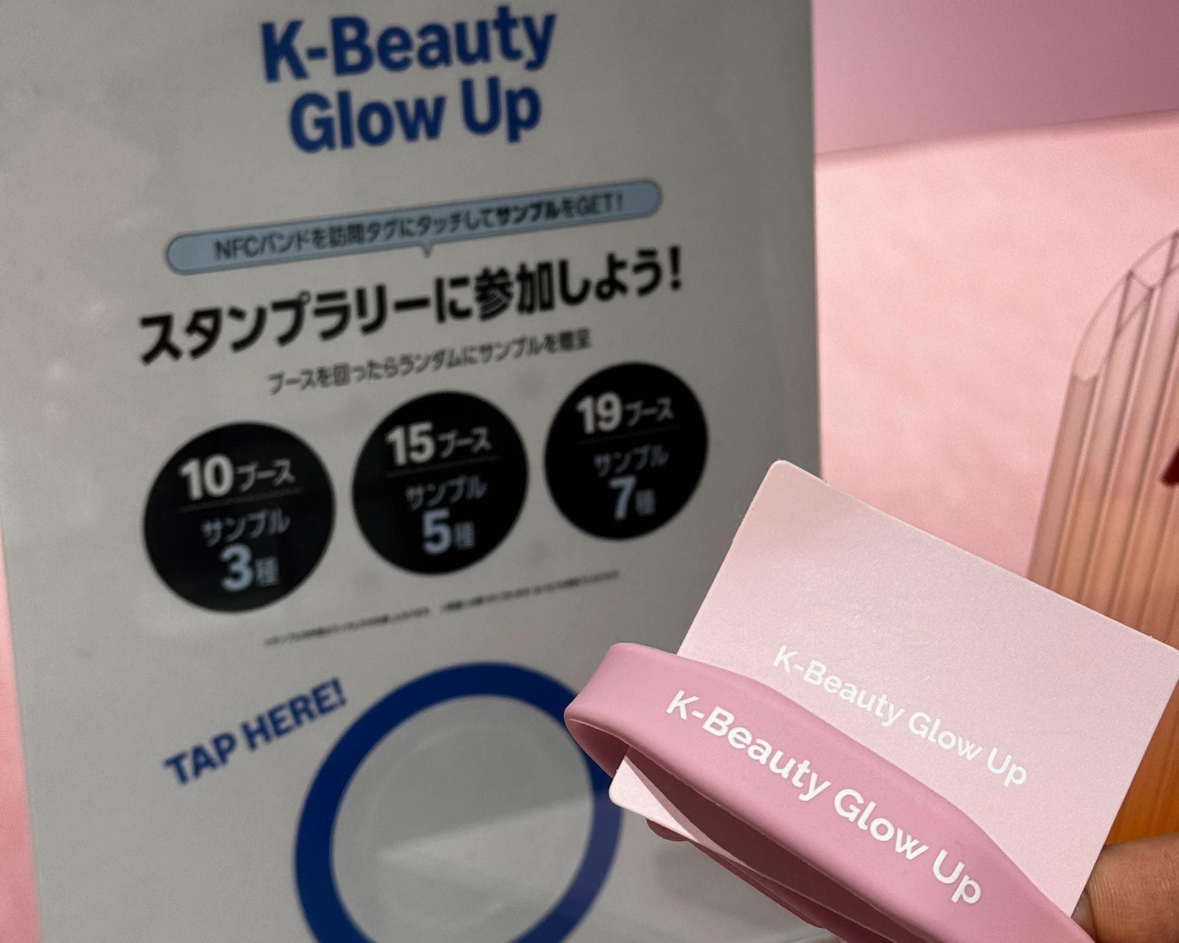 K-Beauty Glow Up のリストバンドと、10・15・19 ブースの特典段階が示されたスタンプラリーの案内サイン